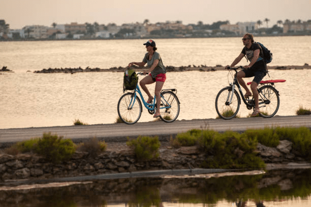 Pareja en bicicleta de alquiler por la carretera de la Savina a la playa de Ses Illestes durante la puesta de sol.