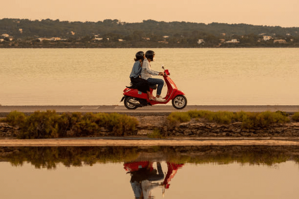 Vespa Primavera 125 con Formentera de fondo en la puesta de sol.